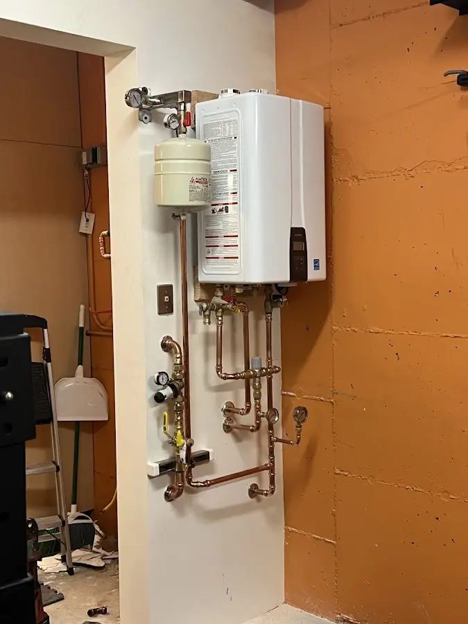 Plumbing technician inspecting water heater connections in Rogers